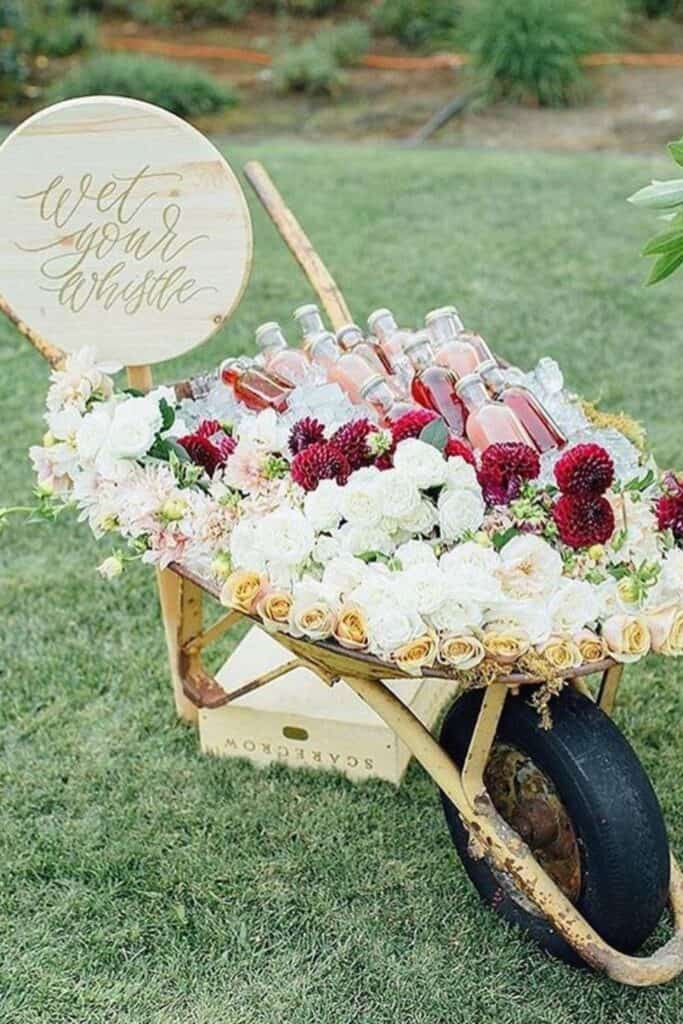 wheelbarrow fridge with beers, ice and flowers in it for garden wedding reception