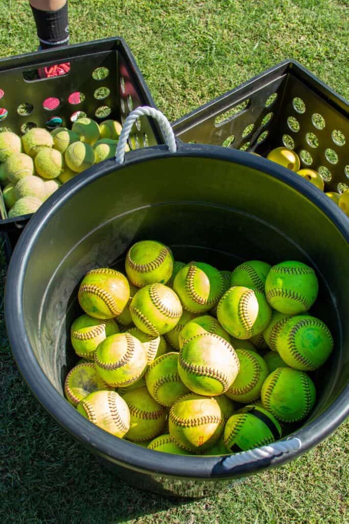 yellow tennis balls in a b bucket on grass for bucket ball game