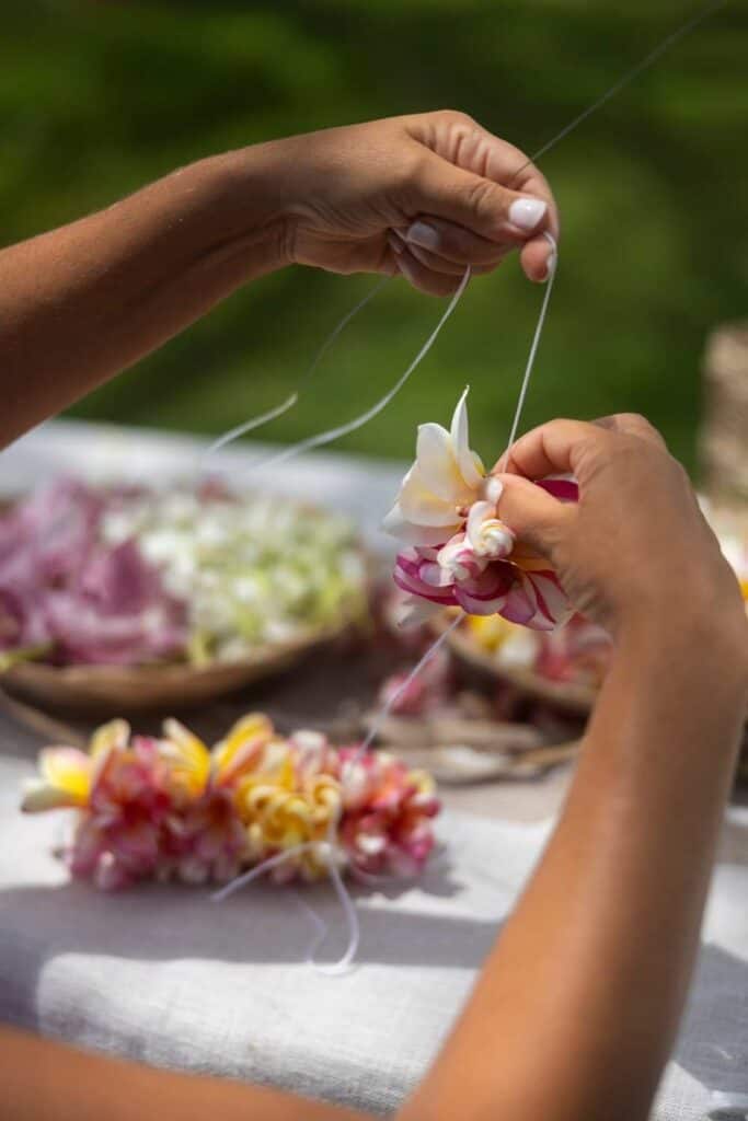 DIY flower crown station - womans hands at a table threading flowers. backyard wedding games 