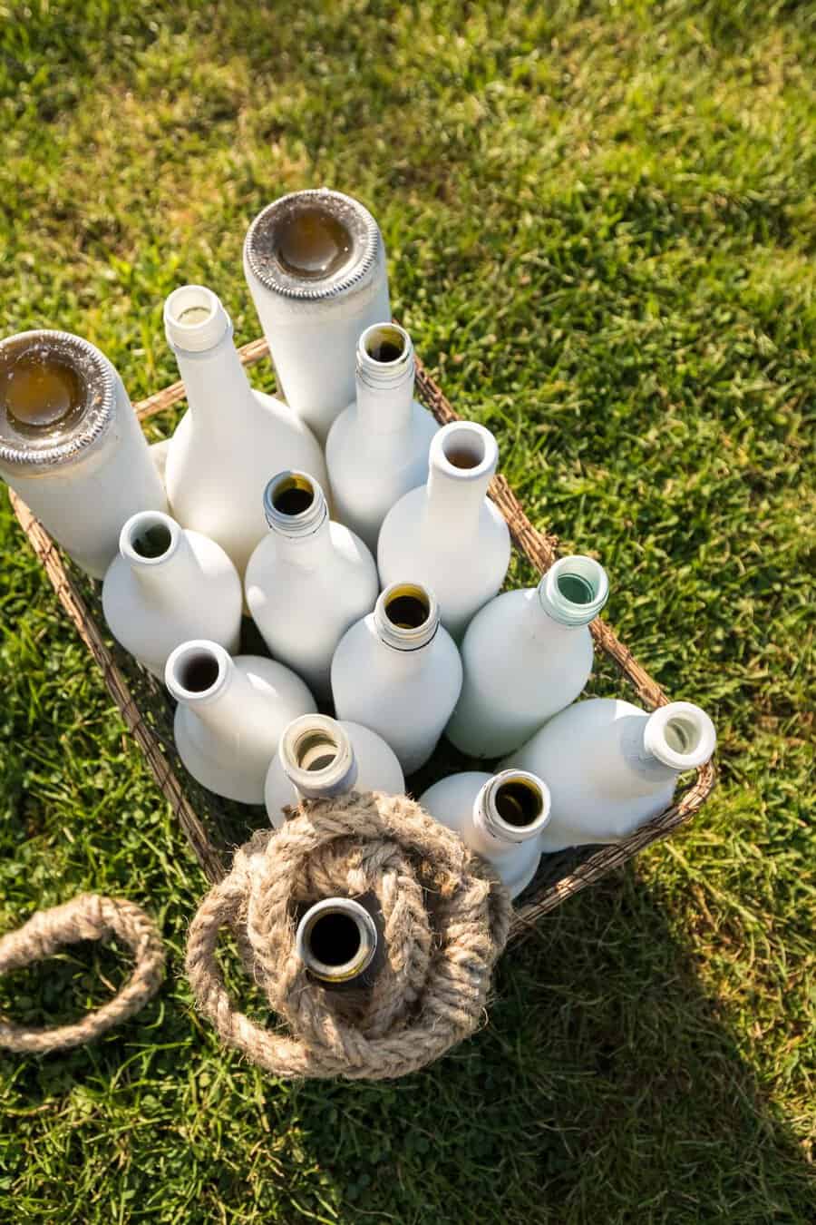 white painted bottles on grass with wooden ropes. For ring toss