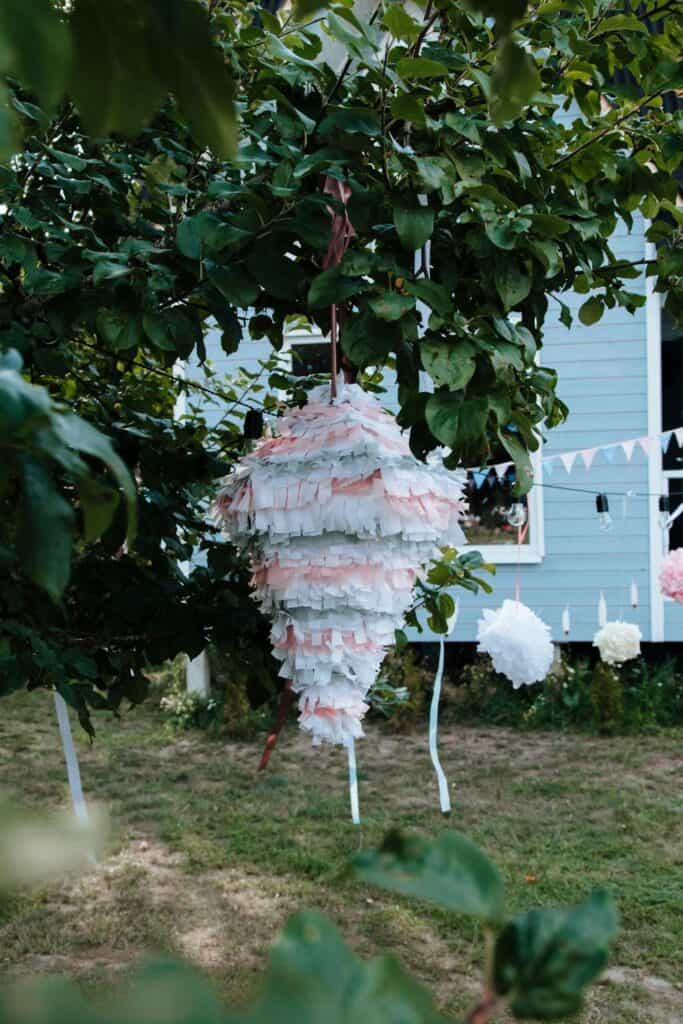 white wedding pinata hanging from tree in backyard